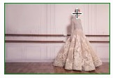 L'image montre une robe élégante en tissu orné, probablement une robe de soirée ou une robe de mariée. La robe a une silhouette ample et raffinée, avec des détails floraux ou des motifs délicats. Elle est présentée contre un fond sobre, ce qui met en valeur sa beauté et son design. L'environnement est lumineux et moderne, ajoutant à l'élégance de la tenue.