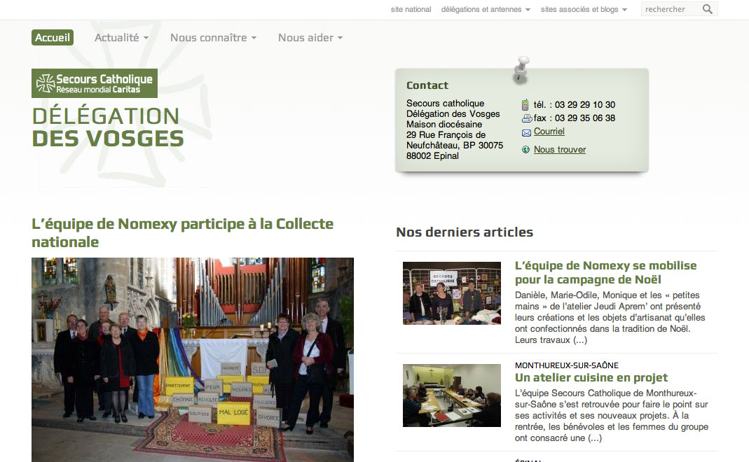 L'image semble être une capture d'écran d'un site web du Secours Catholique, en particulier de la délégation des Vosges. Elle affiche plusieurs sections, dont un menu principal avec des liens vers l'actualité et des informations sur l'organisation. On peut y voir une photo d'une équipe participative qui semble s'impliquer dans une collecte nationale, avec des bénévoles à l'arrière-plan, probablement dans un environnement festif ou communautaire. Le site inclut également des informations de contact et une liste d'articles récents.