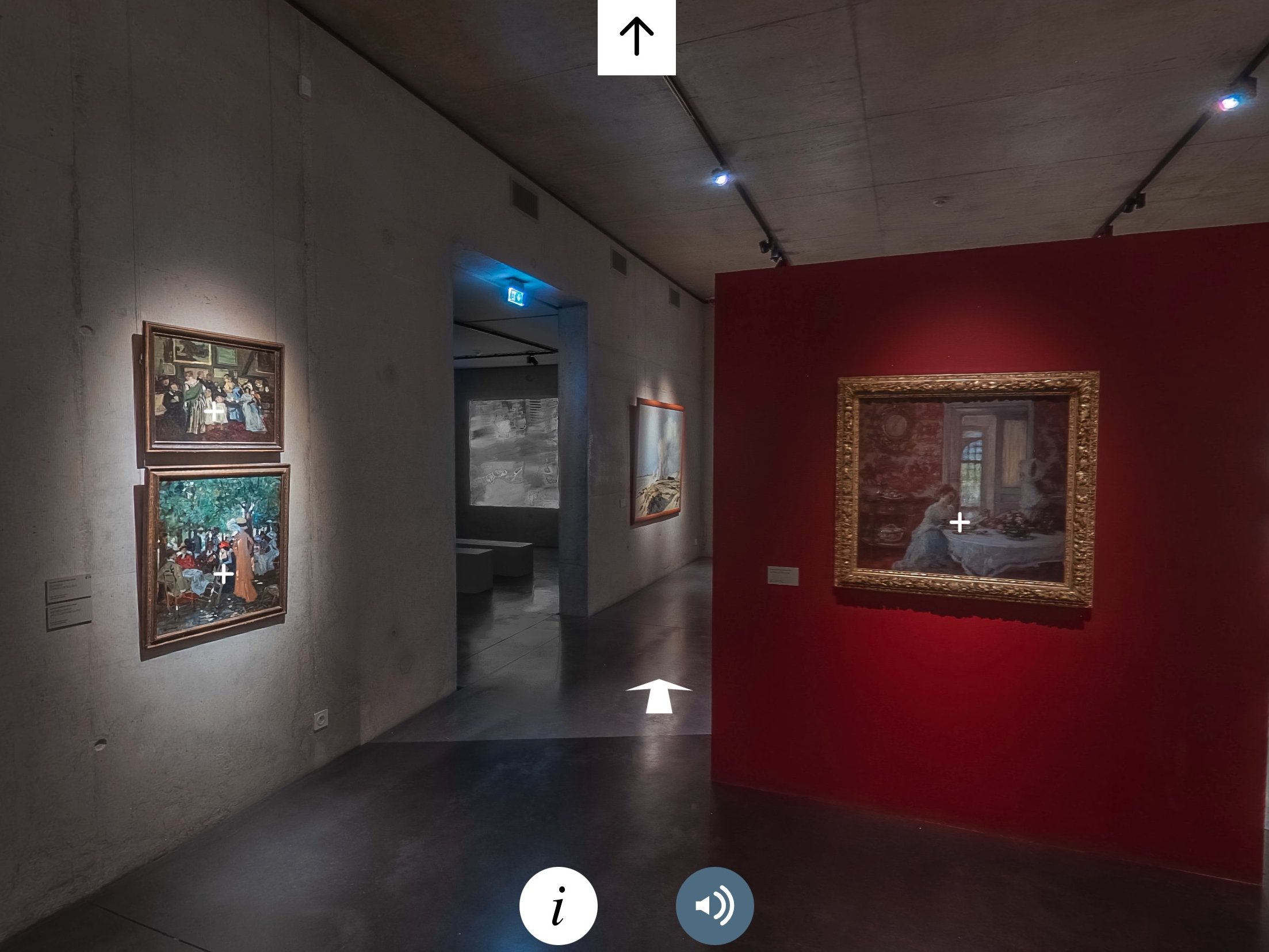 L'image montre une vue intérieure d'une galerie d'art moderne. Sur le mur à gauche, il y a plusieurs tableaux encadrés, tandis qu'un mur de couleur rouge se trouve sur la droite, mettant en valeur un tableau encadré de manière ornate. L'éclairage est tamisé, créant une ambiance intime pour apprécier l'art. On aperçoit également une entrée ou un couloir au fond à gauche, avec des murs aux couleurs neutres et une disposition minimaliste.