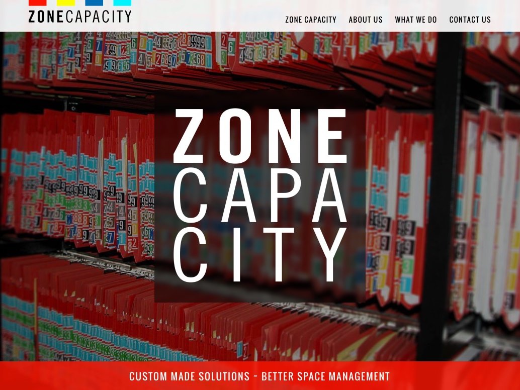 L'image présente un site web intitulé "ZONE CAPACITY". En arrière-plan, on peut voir des rangées de fichiers ou de dossiers organisés sur des étagères, principalement en rouge. Au centre, le nom "ZONE CAPACITY" est affiché en lettres blanches et larges, mettant en avant l'identité de l'entreprise. Le site semble se concentrer sur des solutions sur mesure pour une meilleure gestion de l'espace, comme indiqué par le texte supplémentaire en bas de la page.