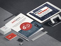 Cette image présente un bureau moderne et bien organisé. Au centre, il y a un document intitulé "data|plana" avec un design graphique, entouré de divers objets de bureau. On voit également une tablette numérique affichant des informations sur le Big Data. À côté, il y a des cartes de visite, un stylo et un clip, le tout sur un fond en béton. L'ensemble dégage une ambiance professionnelle et technologique, axée sur la gestion des données.